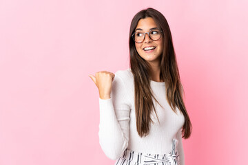 Young brazilian woman isolated on pink background pointing to the side to present a product