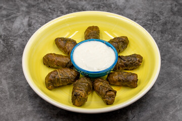 Meat leaf wrapping. Traditional Mediterranean flavor. Wrapped leaves with yogurt on a dark background. local name etli yaprak sarma