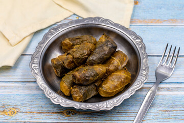 Meat leaf wrapping. Traditional Mediterranean flavor. Wrapped leaves with yogurt on a blue background. local name etli yaprak sarma