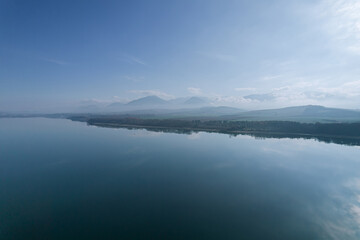 Fog in the mountains, a large lake. Display of trees to the lake.