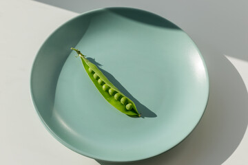 One fresh ripe sweet pea on the green plate. Healthy lifestyle concept.