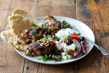 Spicy chicken thighs with Greek salad and pita breads