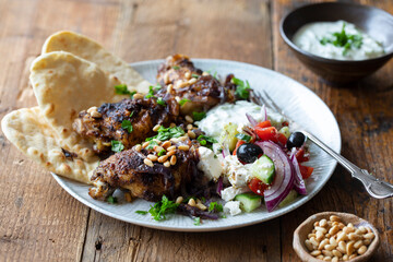 Spicy chicken thighs with Greek salad and pita breads