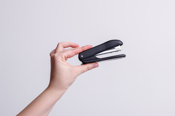 Stapler in the hands of a girl on a white background, stationery