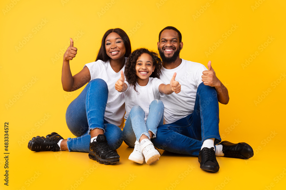 Wall mural excited african american people gesturing thumbs up sitting on floor