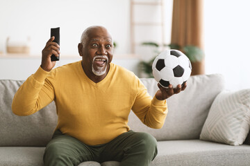 Mature Black Man Watching Sport On TV Celebrating Victory Indoors