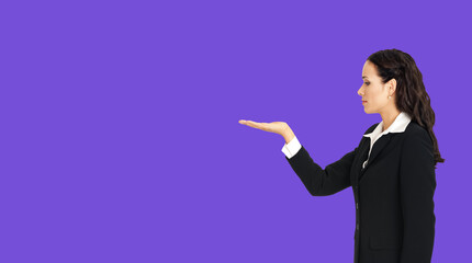 Profile side of beautiful businesswoman showing something or copy spase for product. Brunette woman looking at her hand in business cstudio concept, isolated over violet purple color background.