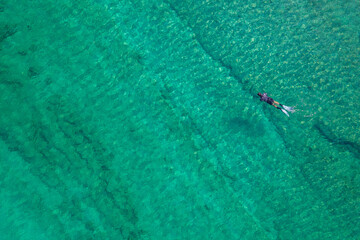 Spearfishing scuba diver in tropical exotic sea, ocean turquoise clear water. Man swimming hunting exotic fish, poaching. Top view. Aerial, drone, copter view.