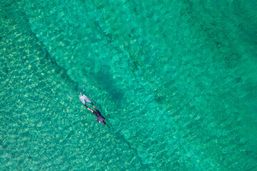 Spearfishing scuba diver in tropical exotic sea, ocean turquoise clear water. Man swimming hunting exotic fish, poaching. Top view. Aerial, drone, copter view.