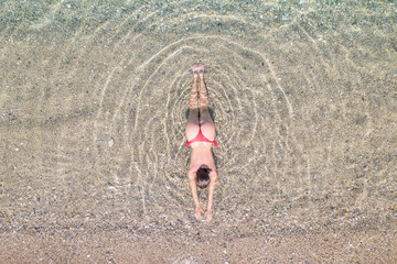 Top, aerial view. Young beautiful woman in a red bikini panties lying and sunbathe in sea water on...