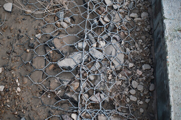 coast strengthening construction made from a metal grid and granite stones. after storm