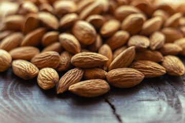 Close up almonds on dark wooden table. Organic health protein vegetarian food. Background copy space
