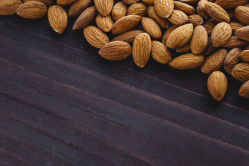 Close up almonds on dark wooden table. Organic health protein vegetarian food. Background copy space