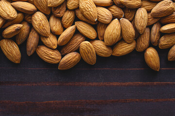 Close up almonds on dark wooden table. Organic health protein vegetarian food. Background copy space