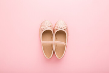 Child shiny low shoes with glitters and straps on light pink table background. Pastel color. Closeup. Top down view.