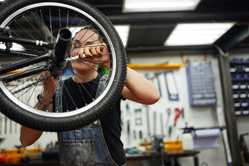 Woman fixing bicycle wheel with wrench