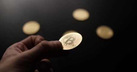 A closeup shot of a hand holding and showing off a gold Bitcoin coin
