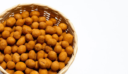 Crispy peanut snack balls in bamboo basket on white background.