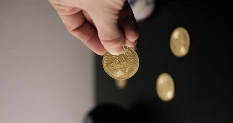A hand picking up a gold Bitcoin coin to show off then placing it back