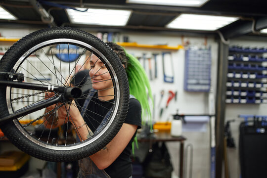 Content woman repairing bicycle wheel