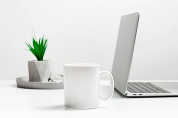 White mug mockup on modern stylish workplace with laptop. Cup mockup.