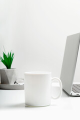Fototapeta na wymiar White mug mockup on modern stylish workplace with laptop. Cup mockup.