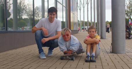 CZ, Kladno, Armenska, 4.8.2021 A team of three people sitting on the sidewalk. They are looking at...