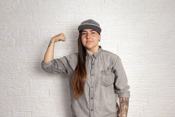 Portrait of alternative woman with cool hairstyle in inspirational pose showing flexed arms.