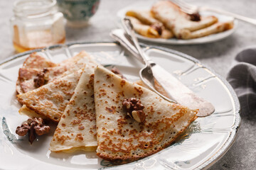 Homemade pancakes with nuts and honey on a gray textured background