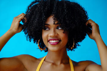 headshot young beautiful woman with hands in curly hair afro hairstyle looking to the side at copy space posing in studio