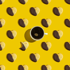 Seamless pattern with cup of coffee and heart shaped cookies on yellow background.