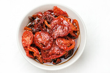 Sun dried tomatoes  on white bowl, white wooden background. Dried tomatoes  recipe.  Top view,  copyspace.