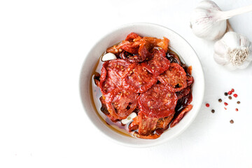 Sun dried tomatoes  on white bowl, white wooden background. Dried tomatoes  recipe.  Top view,  copyspace.