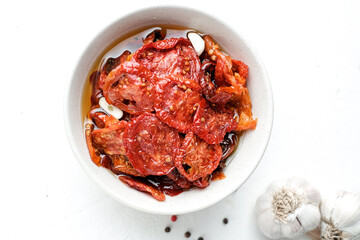 Sun dried tomatoes  on white bowl, white wooden background. Dried tomatoes  recipe.  Top view,  copyspace.