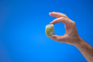 Cube of delicious green colored Turkish Delight held in male hand. Close up studio shot, isolated...