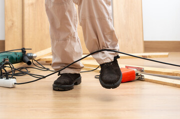 Close up of a carpenter legs stumbling with an electrical cord at house