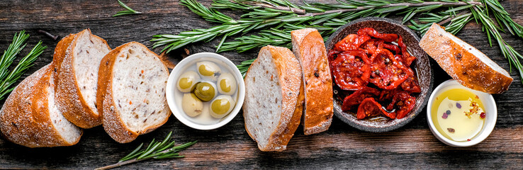 Italian ingredients  food background. Slices of ciabatta bread  on wooden board with olives, dried...