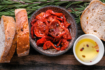 Italian ingredients  food background. Slices of ciabatta bread  on wooden board with olives, dried tomatoes, oil, rosemary and herbs on rustic wooden background. top view.
