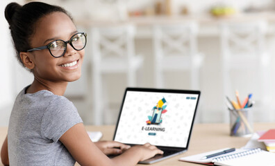 Smiling teenage african american cute girl pupil in glasses study online at home
