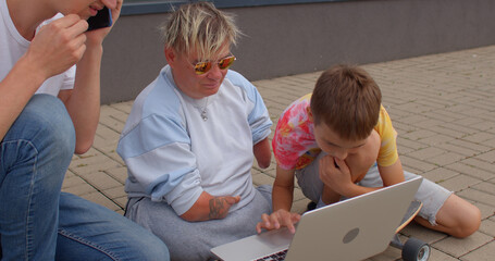 Using a laptop on the sidewalk. A teenager uses a keyboard to control a computer. Installing a new...