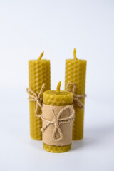 three beeswax candles tied with twine on a white background. natural wax