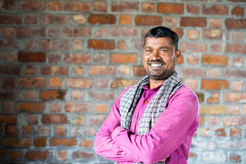 Smiling confident construction worker turns by looking camera at workplace - concept of manual labor and happiness