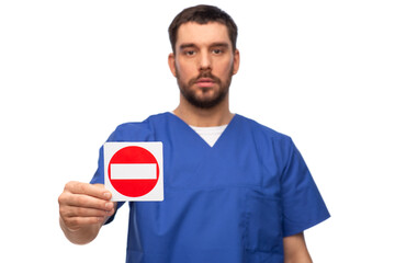 healthcare, profession and medicine concept - male doctor in blue uniform showing stop sign over...