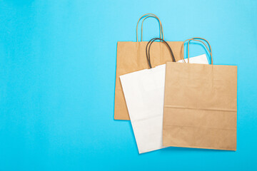 Blank brown paper carrier bag with handles for shopping, facing front on blue background