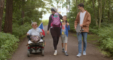 A disabled woman walks in a wheelchair in the park with relatives. Take time for all family...
