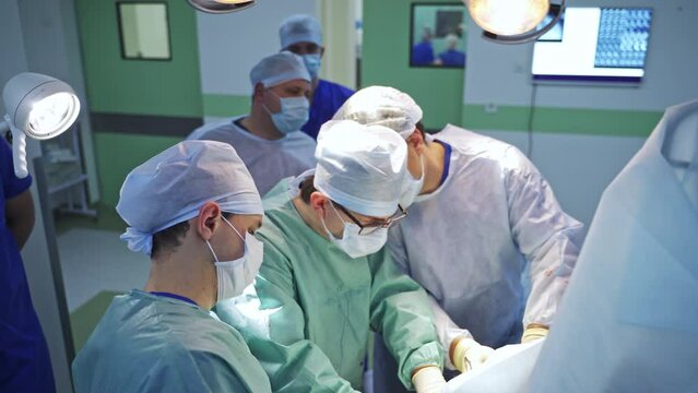 Group of three surgeons work hard at operation. Many professionals gathered in operational theater for hard case surgery.