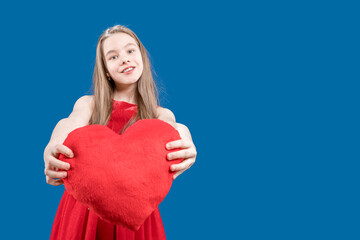 Valentine's day. Declaration of love. Heart shaped postcard. A cute girl holds a big heart in her hands and stretches it forward. Copy space.