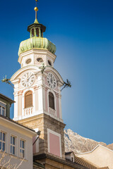 Fototapeta na wymiar Tower clock on city hall in Innsbruck, Austria. Innsbruck landmark on sunny day in winter. Ancient church and Alps mountains on background, Innsbruck. Historical architecture in Tyrol, Austria.