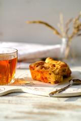 Culinary template. Homemade Charlotte apple pie on a wooden round plate with tea, spoon, napkin and a vase with dry flowers. Cozy breakfast. Sweet organic plant-based traditional bakery. Empty space.