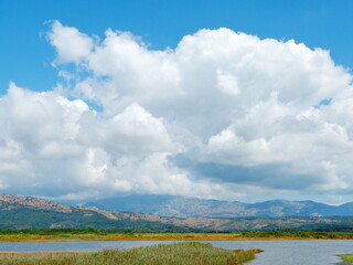 Beautiful sky cloudscape over lake and mountains in Solana Bajo Sekulic nature reserve, Ulcinj, Montenegro.